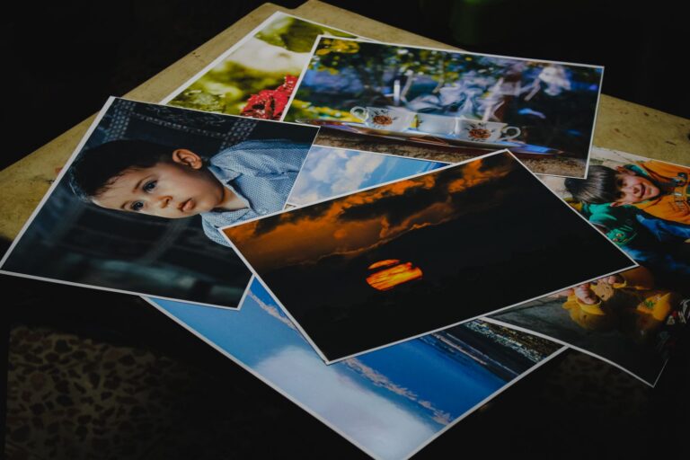 Vytlačené fotografie portrétov a krajiny rozložené na stole.