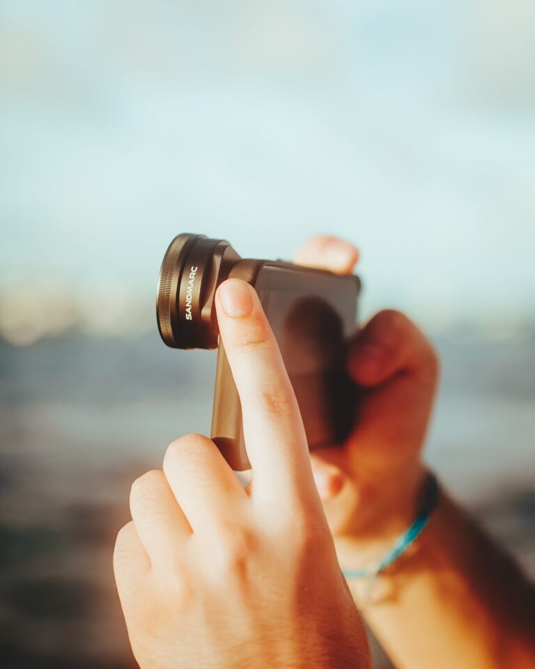 Fotografovanie mobilom s prídavným objektívom v rukách.