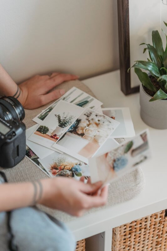 Ruky porovnávajú vytlačené fotografie pri stole; ilustračná licencovaná fotografia.