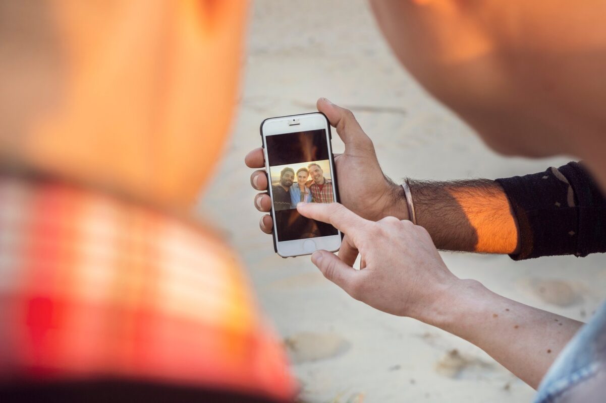 Ľudia si prezerajú fotografiu na displeji mobilného telefónu.
