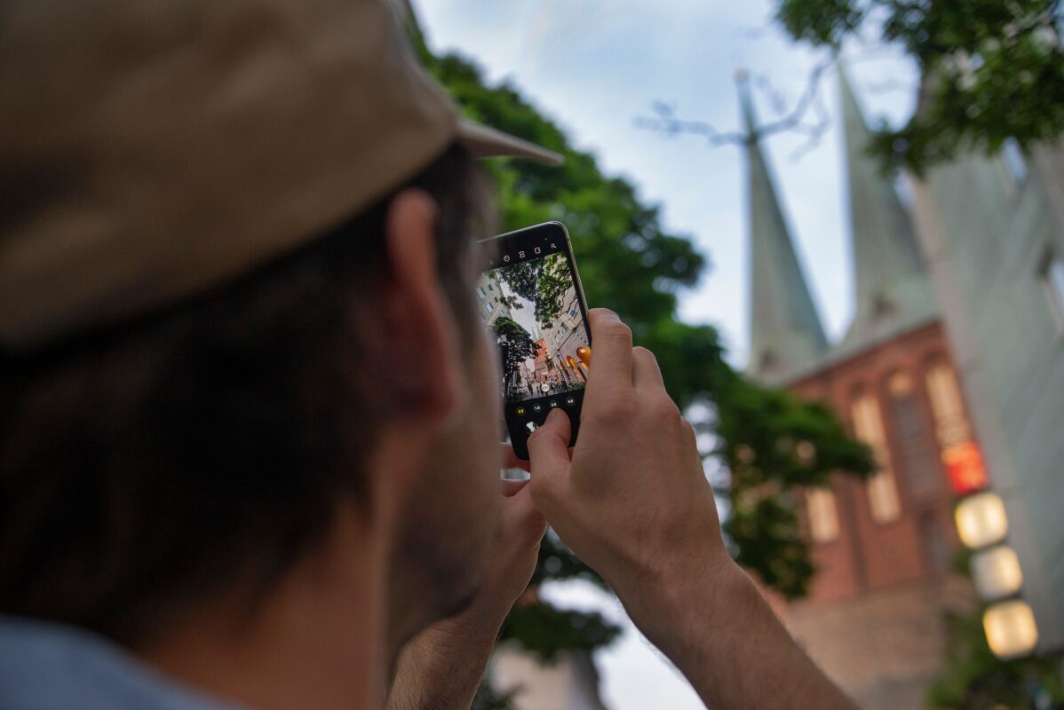 Osoba fotí architektúru mobilom; stabilný záber pomáha zachovať ostrosť aj pred tlačou fotografie