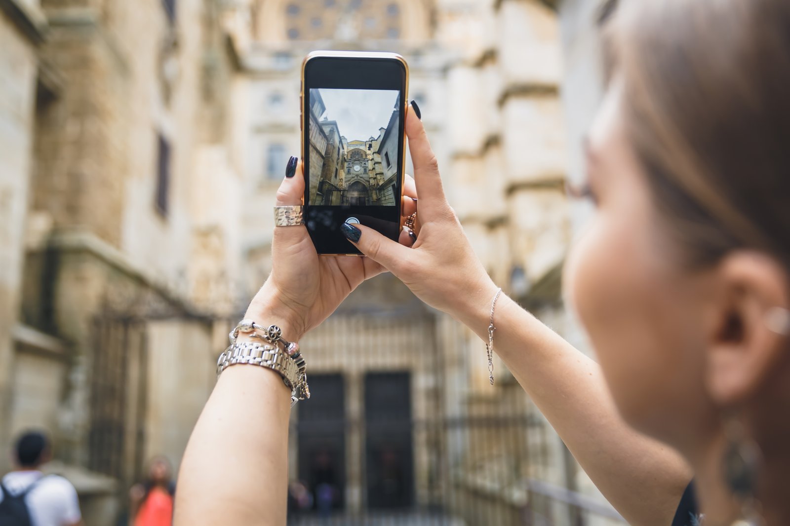 Žena fotografuje budovu mobilným telefónom a kontroluje záber na displeji.