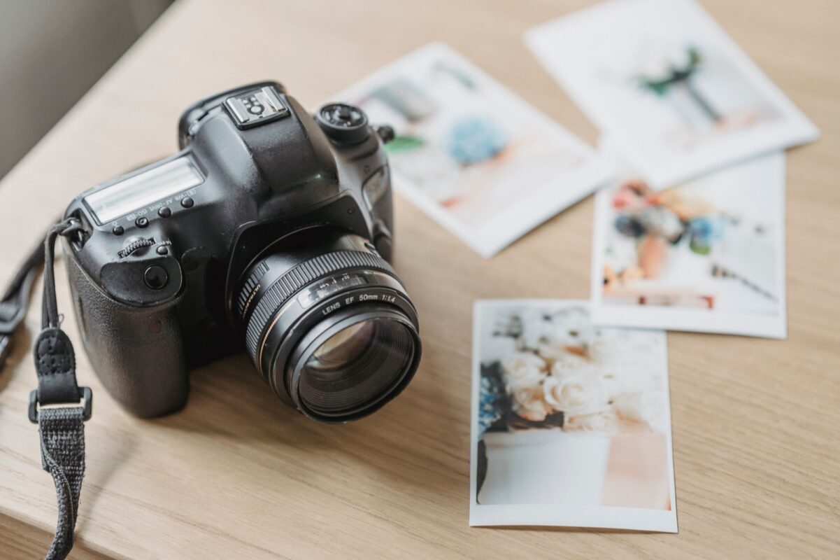 Fotoaparát a vytlačené fotografie rozložené na stole.